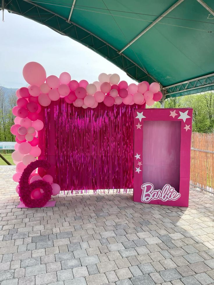 balloons and streamers decorate the entrance to a barbie birthday party