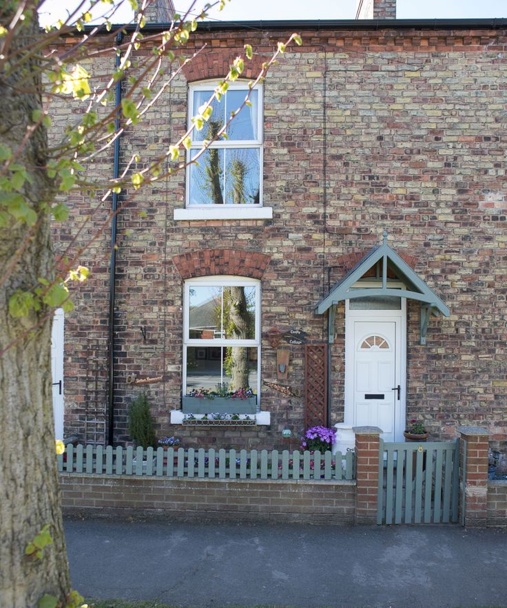 a brick house with a white front door and fenced in area next to it