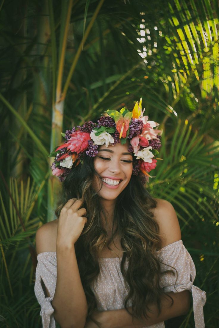 a woman with flowers in her hair smiles at the camera while wearing a flower crown