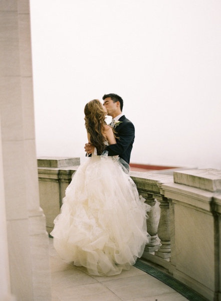 a bride and groom kissing on the roof of a building