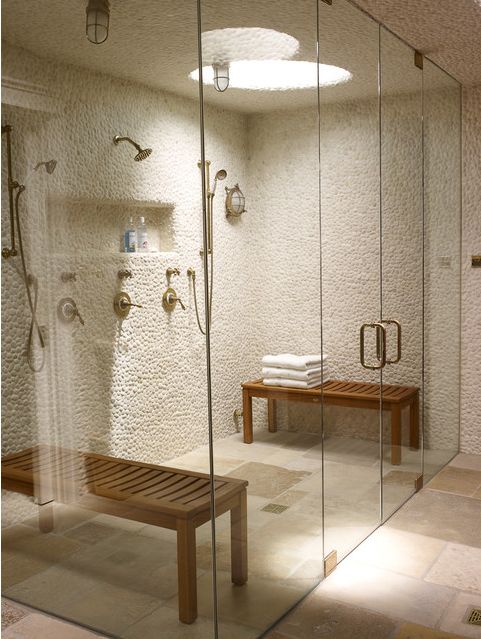 a bathroom with a bench and shower in the corner, all glass walls are white