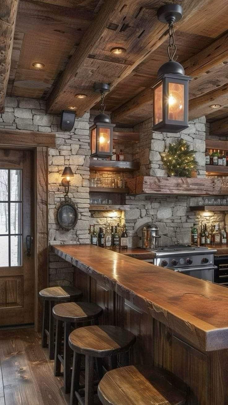 a rustic kitchen with stone walls and wood flooring, bar stools and lights hanging from the ceiling