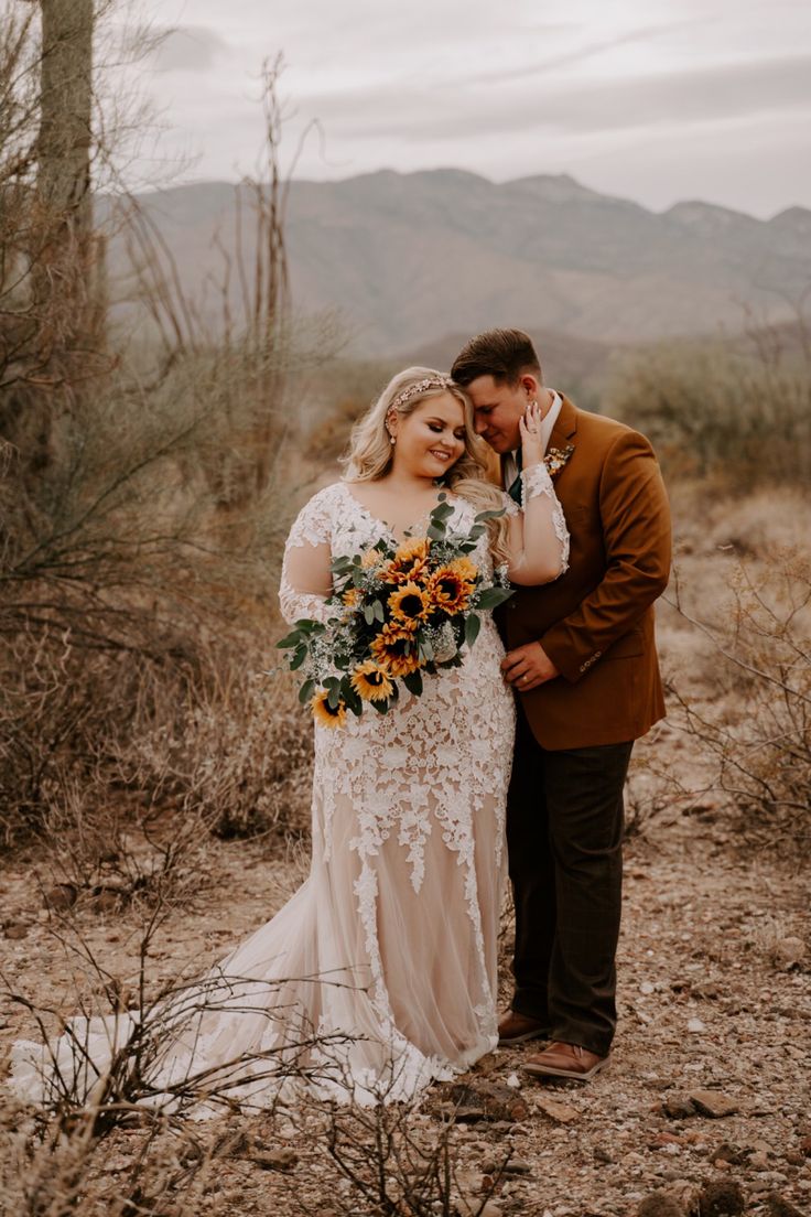 a bride and groom standing in the desert with sunflowers on their wedding day