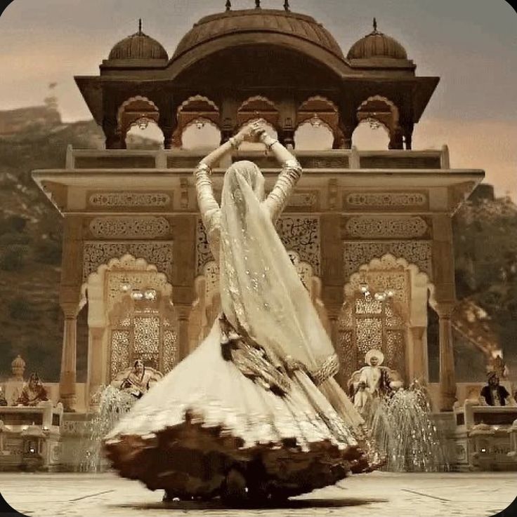 a woman is dancing in front of an ornate building with fountains and people around her