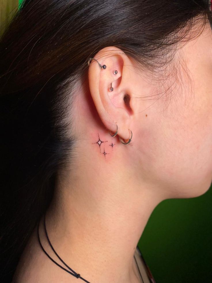 a woman's left ear has a star tattoo on it