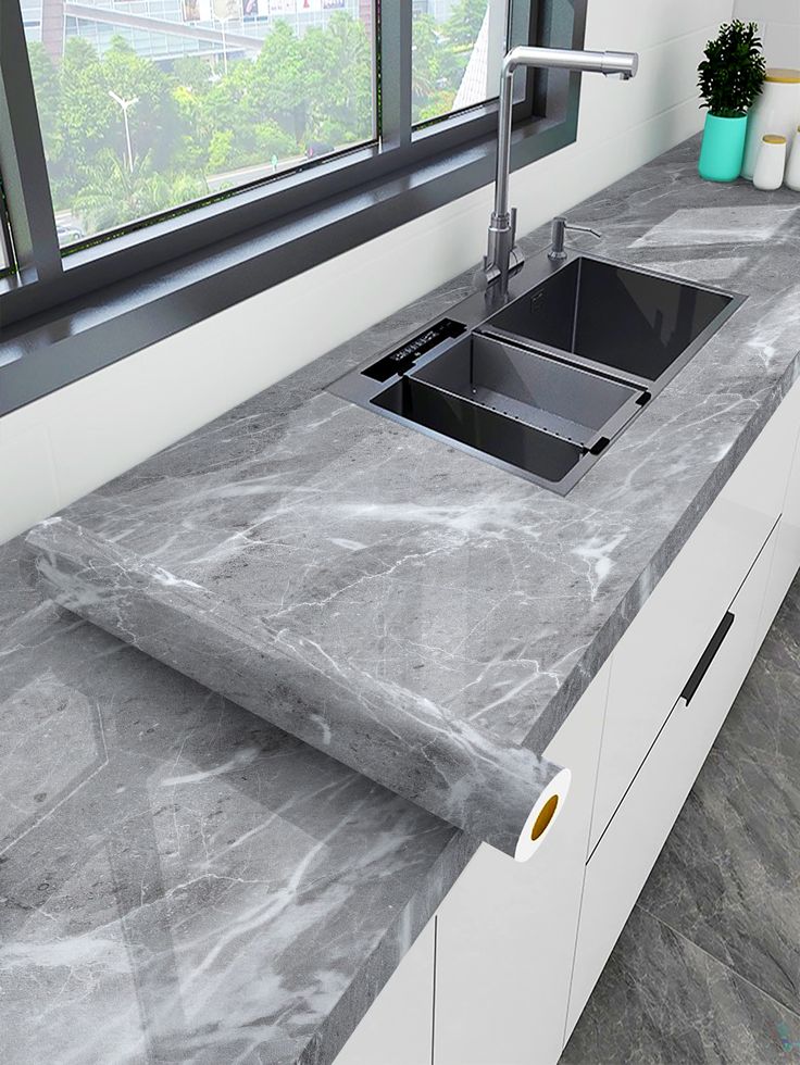 a kitchen counter with a sink and window in the backround, next to an open window