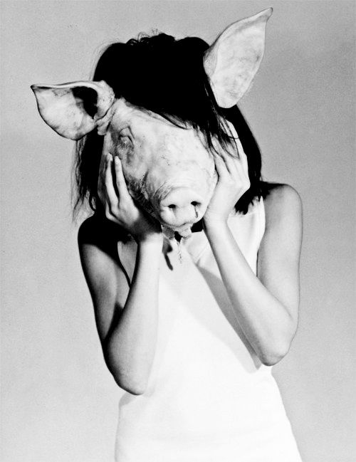 a woman in white shirt holding up pig's head