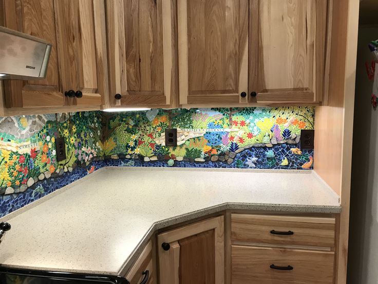 a kitchen with wooden cabinets and colorful tile backsplash inlays on the wall