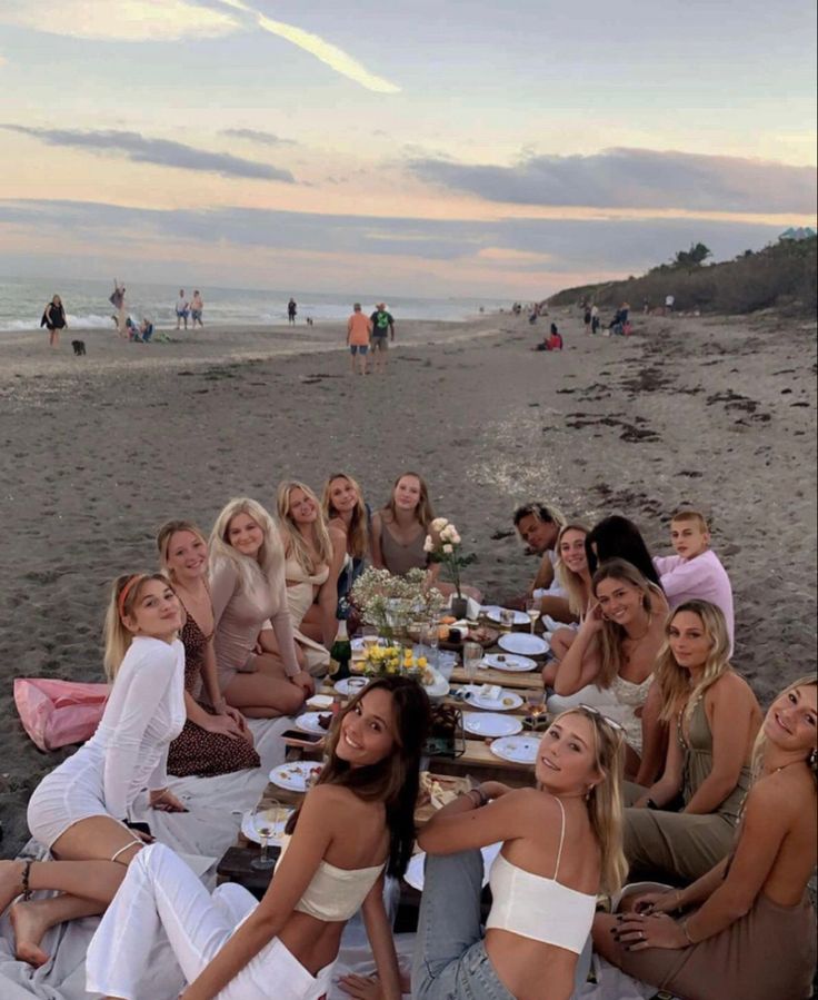 a group of women sitting at a table on the beach