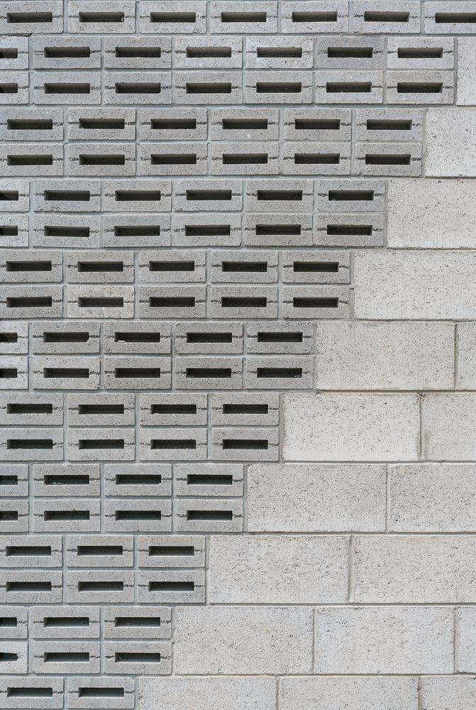 a brick wall that has holes in it and is made up of cement blocks with black grates