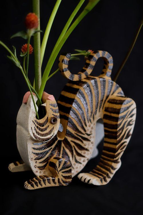 a vase with some flowers in it and a tiger figurine