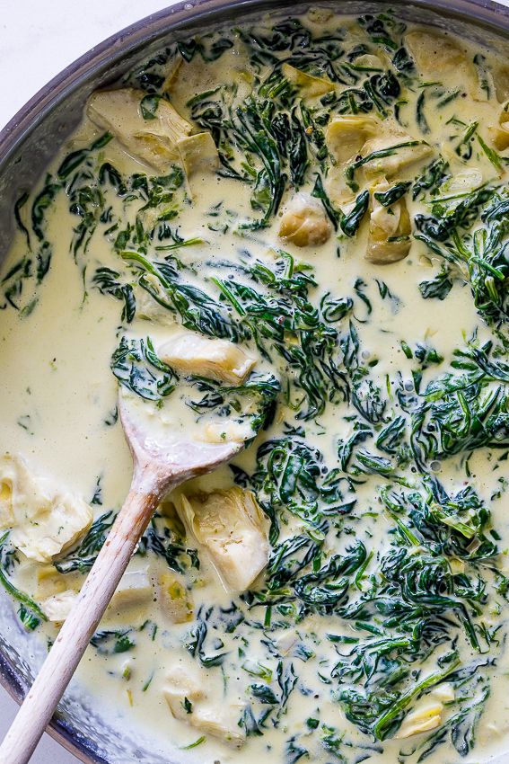 a pan filled with cheese and spinach covered in sauce