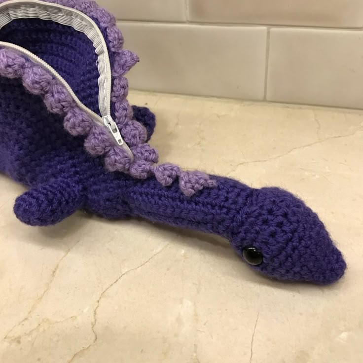 a purple crocheted toothbrush holder sitting on top of a white tile counter