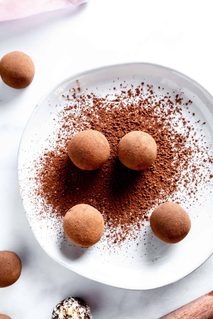 chocolate truffles on a white plate surrounded by cinnamon sticks and powdered sugar