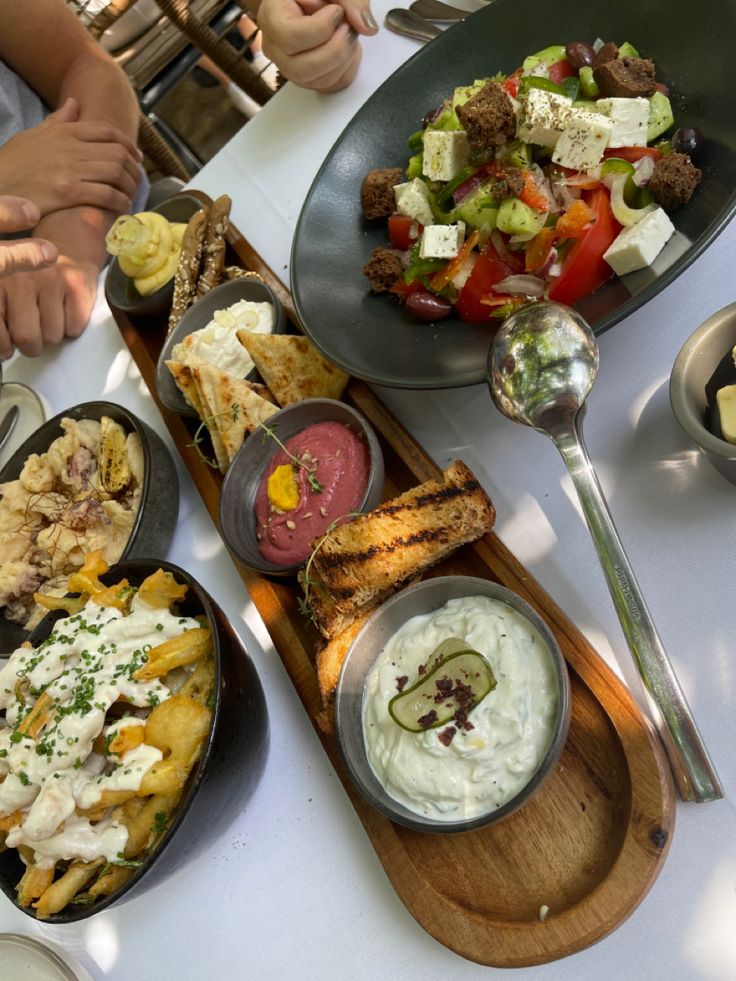 a table topped with plates of food and bowls of dips next to each other