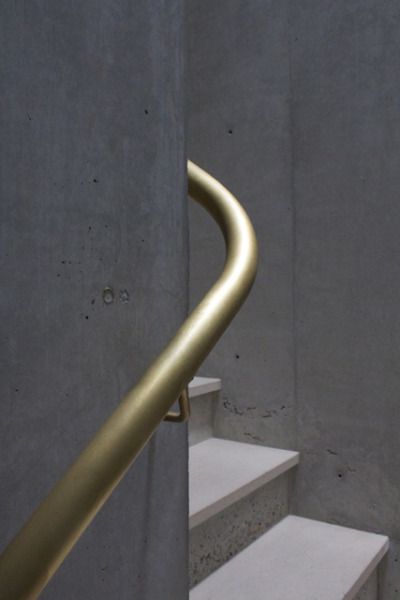 a close up of a metal hand rail on some steps with concrete walls in the background