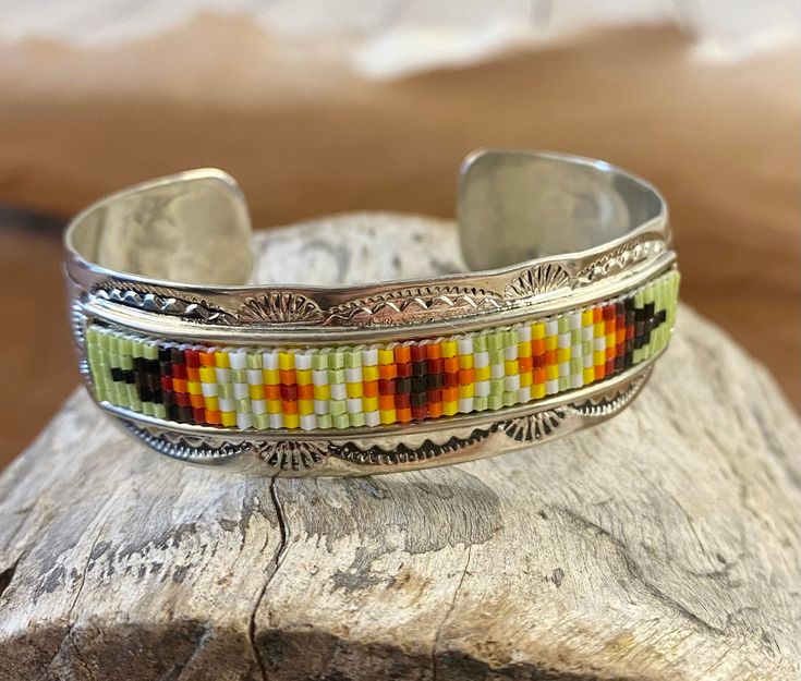 Beautiful unique stamped Nickle sliver and signed by Native American artist Geraldita Whitehorn inside of the cuff band. Aztec seed beaded bright colorful Nickle silver cuff bracelet.  Size: 5” inches inside measurement - gap 1-1.5” inches  Seed Bead Aztec Beaded Cuff Native American Made Unique Bracelet Unique Cuff Bracelet With Round Beads For Festivals, Southwestern Style Silver Beaded Bracelets For Gift, Handmade Adjustable Sterling Silver Artisan Bracelet, Adjustable Cuff Bracelet With Silver Beads As A Gift, Silver Beaded Cuff Bracelet For Festival, Adjustable Silver Beads Cuff Bracelet As Gift, Bohemian Beaded Sterling Silver Bracelet Gift, Bohemian Beaded Sterling Silver Bracelet For Gifts, Southwestern Silver Beaded Bracelet For Gift