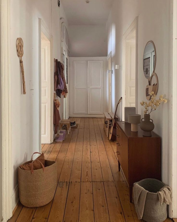 an empty hallway with wooden floors and baskets on the floor in front of it,