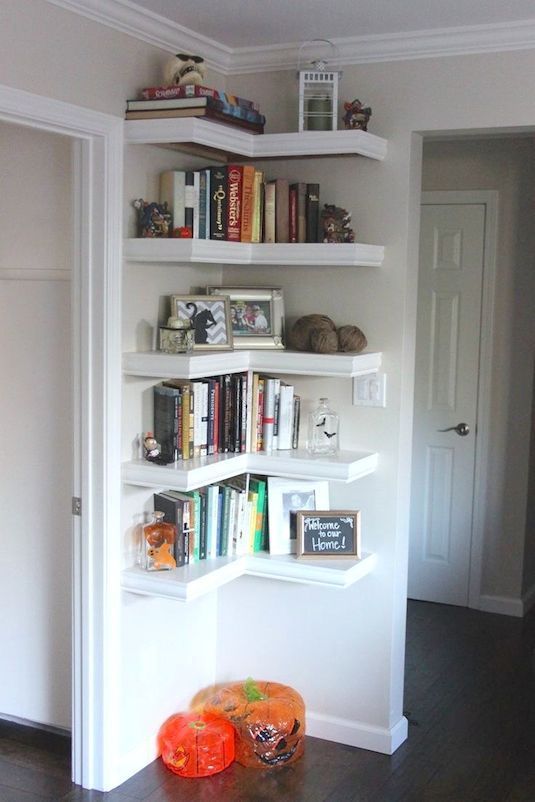 there is a bookshelf in the room with many books on it and two orange pumpkins