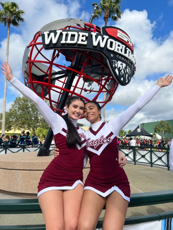 two cheerleaders pose in front of the wide world sign