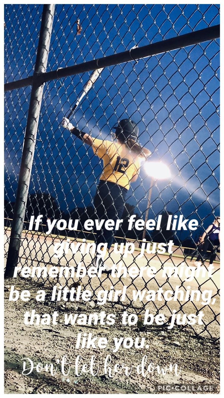 a man holding a baseball bat standing next to a fence with a quote on it