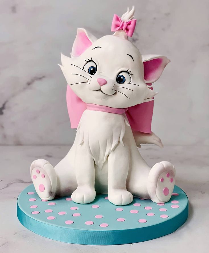 a white cat figurine sitting on top of a blue plate with pink polka dots