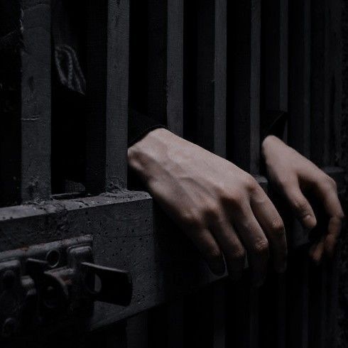 a person's hand on the bars of a jail cell, with their hands hanging out