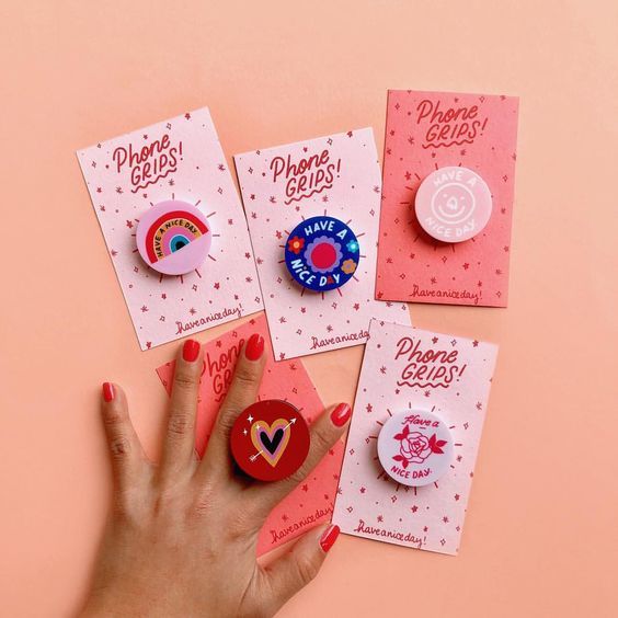 a person's hand is shown with pins and magnets on pink paper next to each other