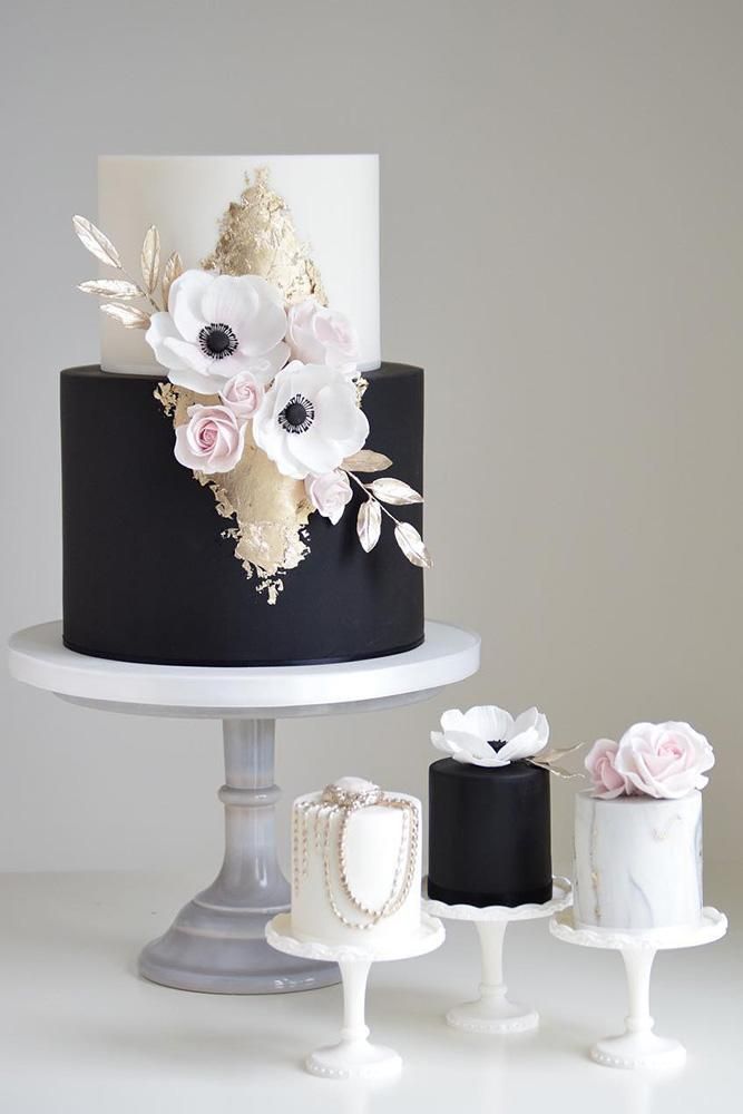 three tiered black and white cake with flowers on top