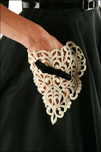 a hand holding onto a piece of white material with intricate designs on it's arm