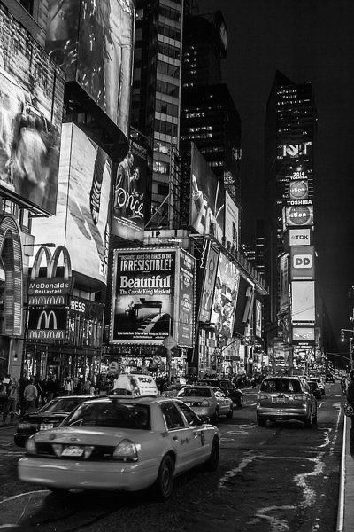 black and white photograph of times square in new york city at night with billboards