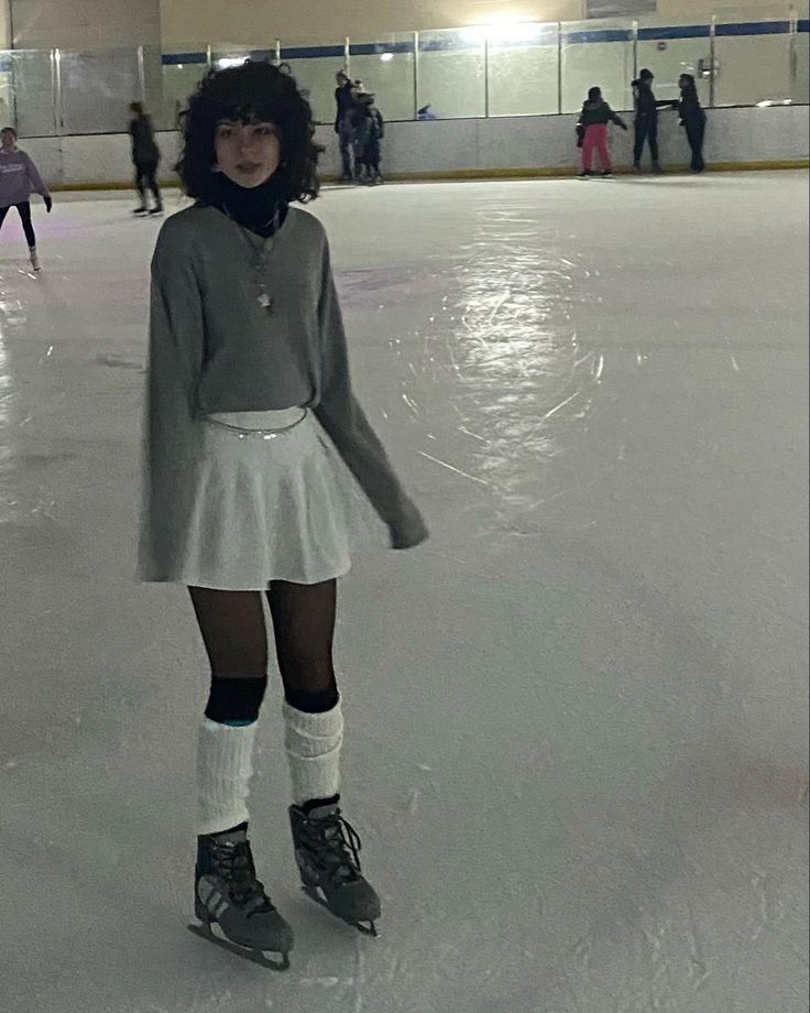 a woman standing on top of an ice rink wearing knee high socks and short skirt