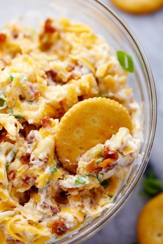 a glass bowl filled with pasta salad and crackers