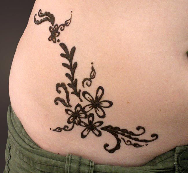 a woman's stomach with an intricate tattoo design on the back of her belly