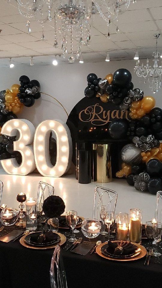 the table is set up with black and gold balloons, candles, and decorations for an 80th birthday party