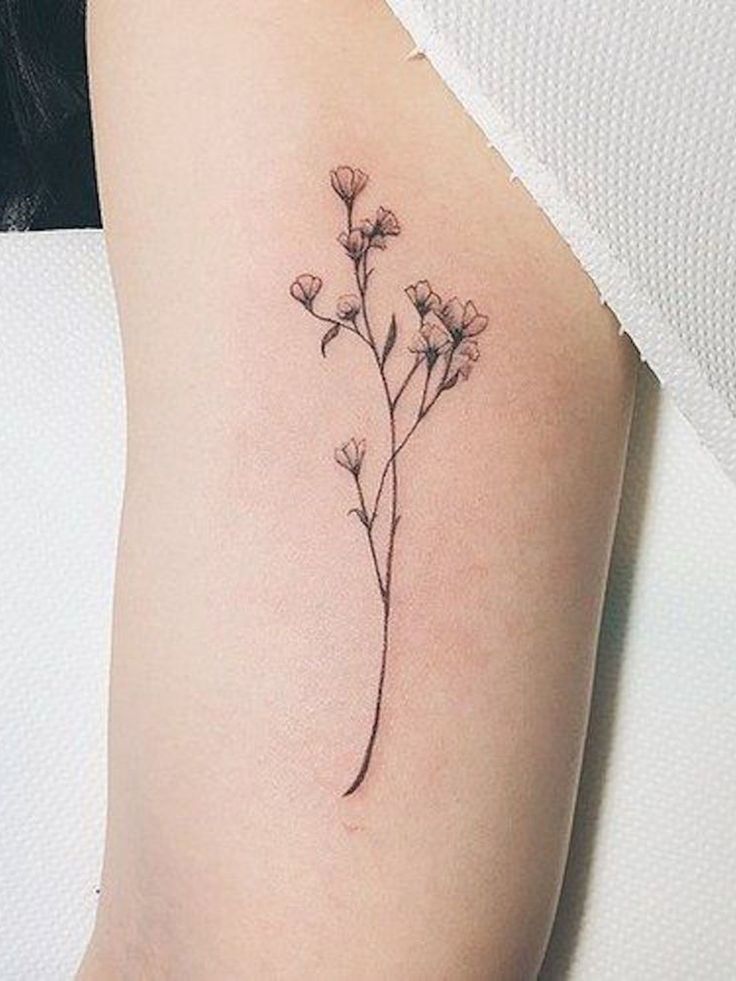 a small flower tattoo on the right side of the arm is shown in black and white