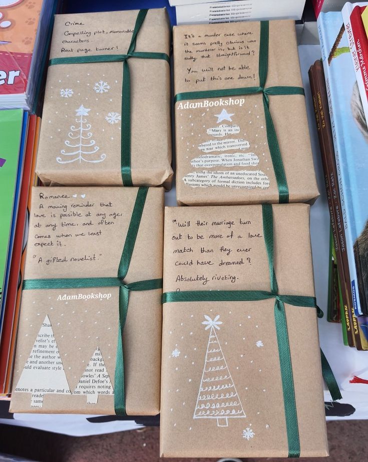 four brown wrapped presents sitting on top of a table next to books and pencils