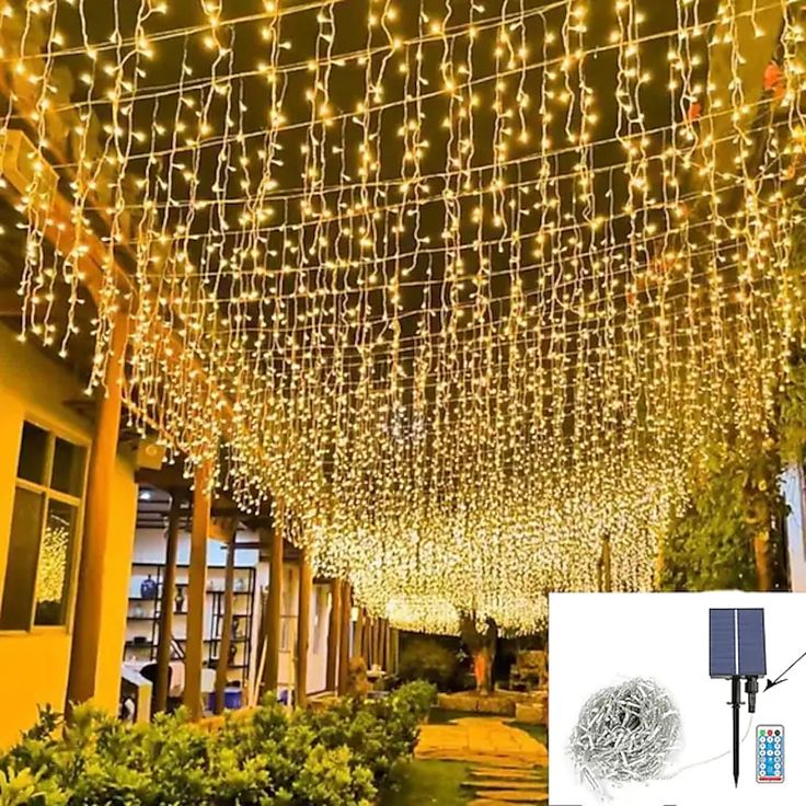 the lights are hanging from the ceiling in front of a building with plants and bushes