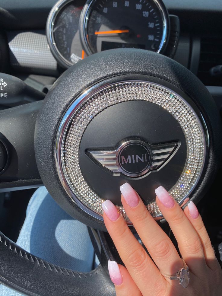 a woman's hand on the steering wheel of a mini cooper with diamond detailing