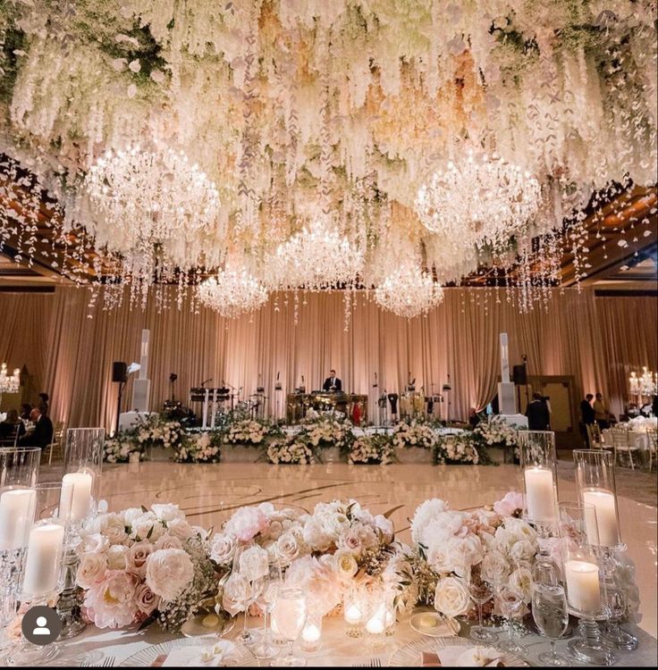 a large chandelier hanging from the ceiling over a table with flowers and candles