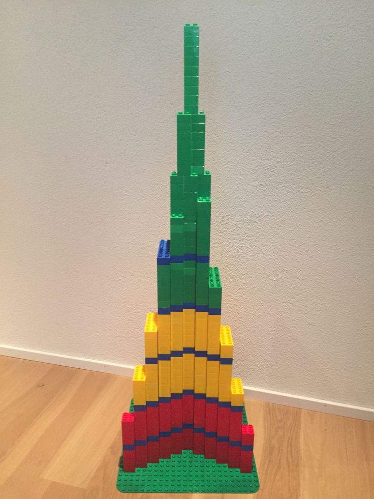 a lego tower made out of blocks sitting on top of a hard wood floor next to a white wall