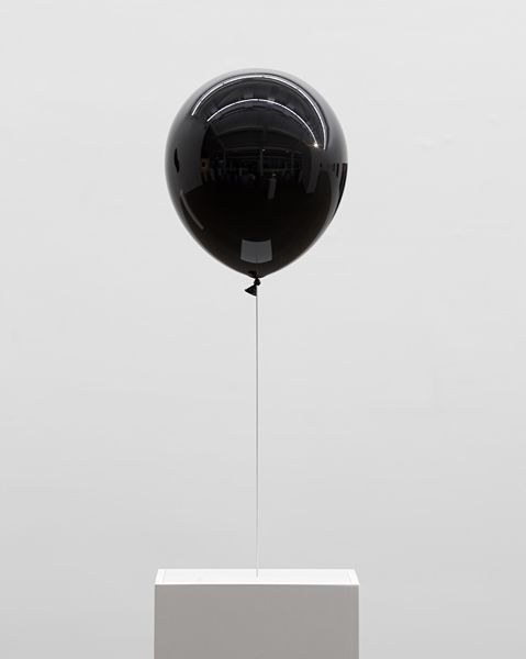 a black balloon floating in the air over a white box