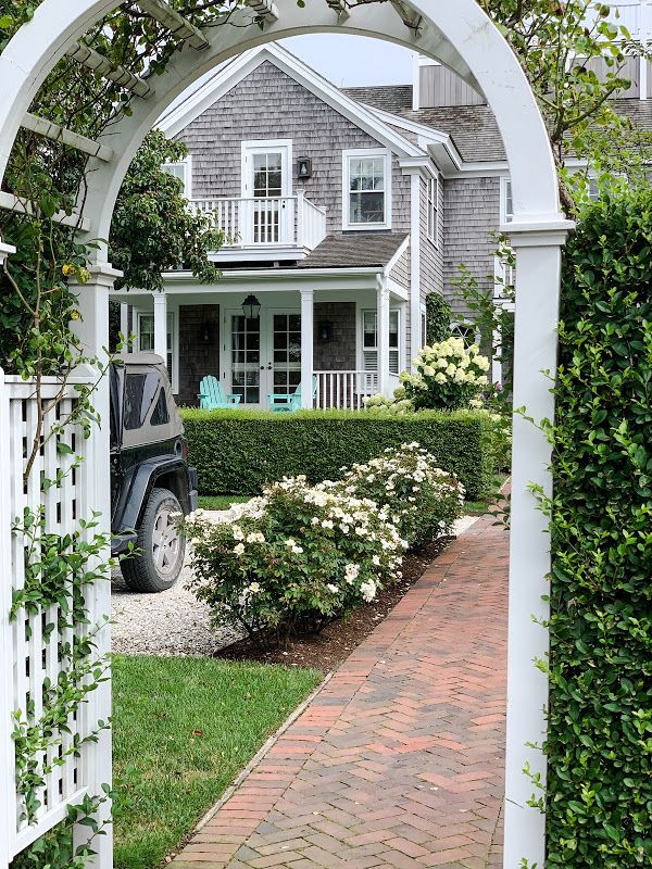 a car parked in front of a house with a white arbor on the side walk