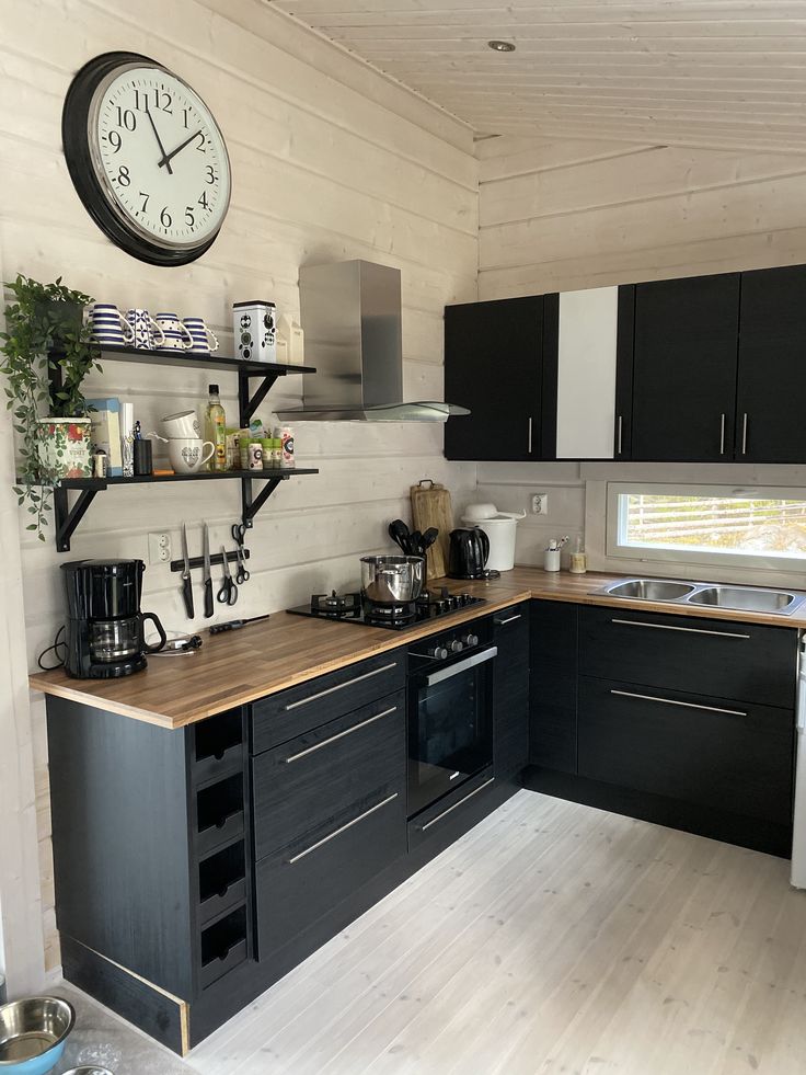 a kitchen with black cabinets and a clock on the wall above the stove top oven