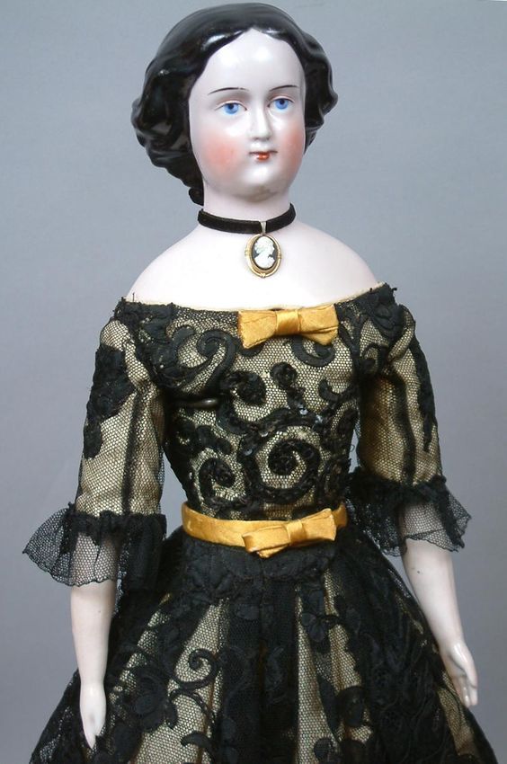 a doll wearing a black and gold dress with lace on it's skirt,