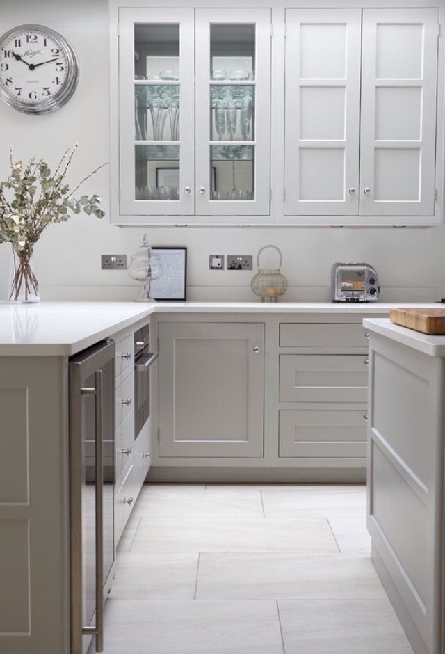 a kitchen with white cabinets and gray counter tops, an island in the middle has a clock on it