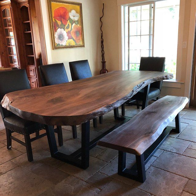 a large wooden table sitting in front of a window next to two black leather chairs