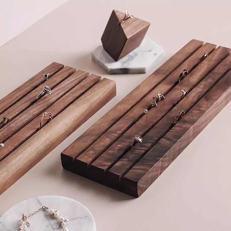 two wooden jewelry racks sitting on top of a table next to a white marble plate