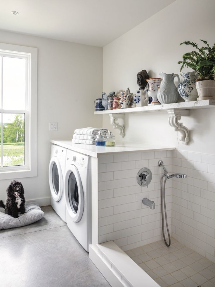 a washer and dryer in a white bathroom with tile flooring, open shelving