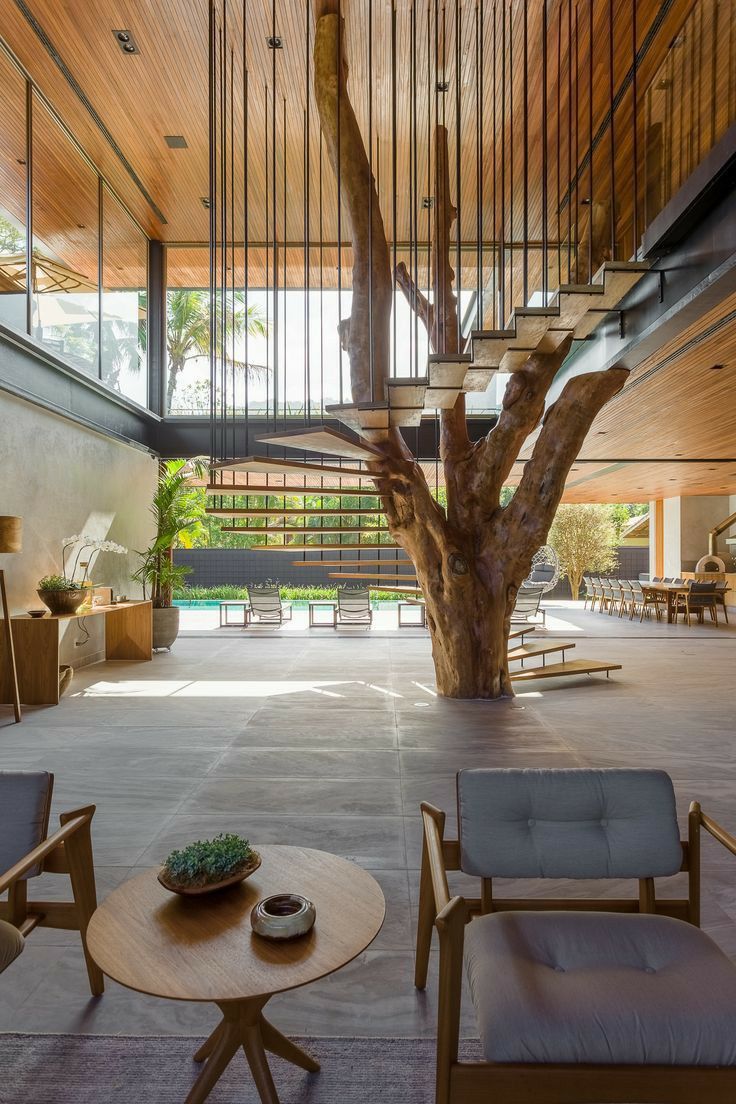 the interior of a modern house with wooden floors and stairs leading up to an indoor tree